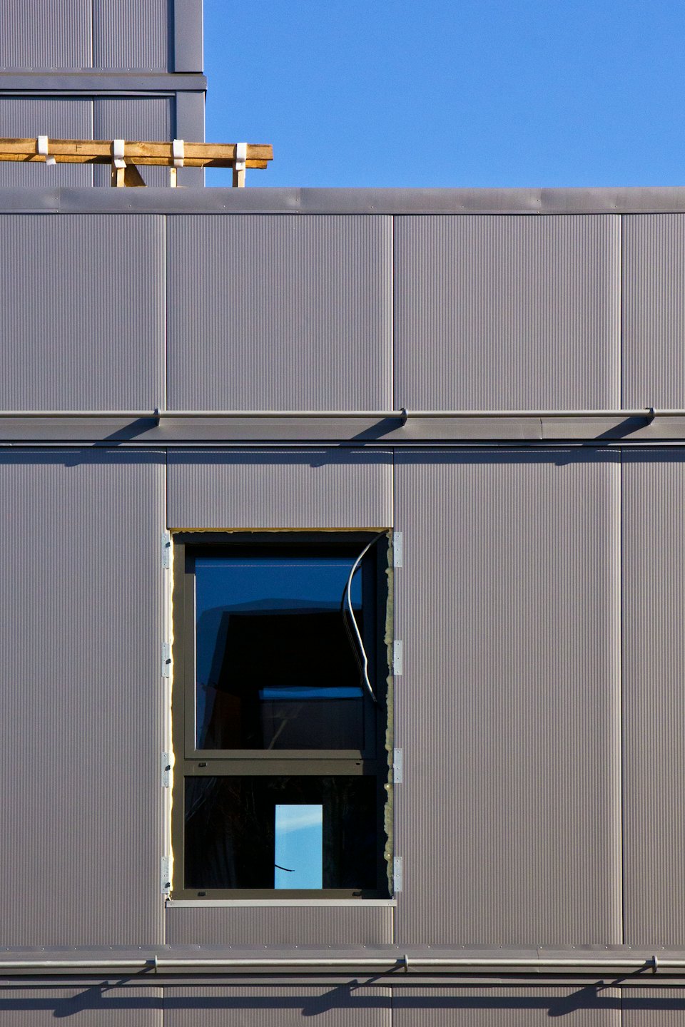 Facciata di un edificio moderno con nuove finestre e pannelli in metallo ondulato.