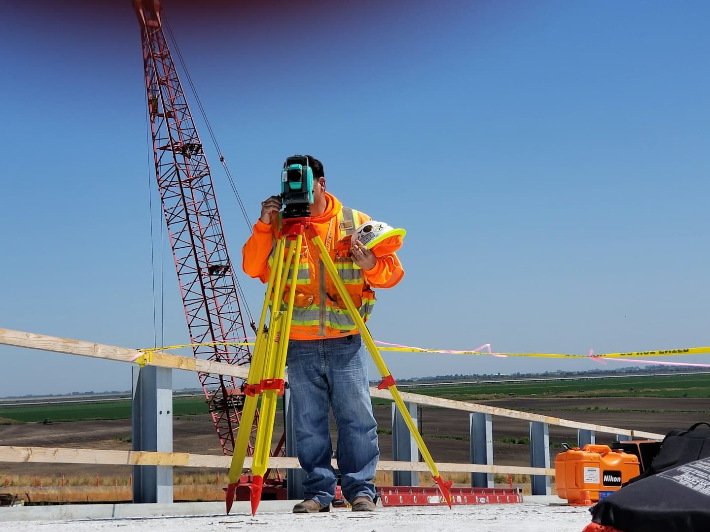Geometra al lavoro con strumentazione in un cantiere con gru.